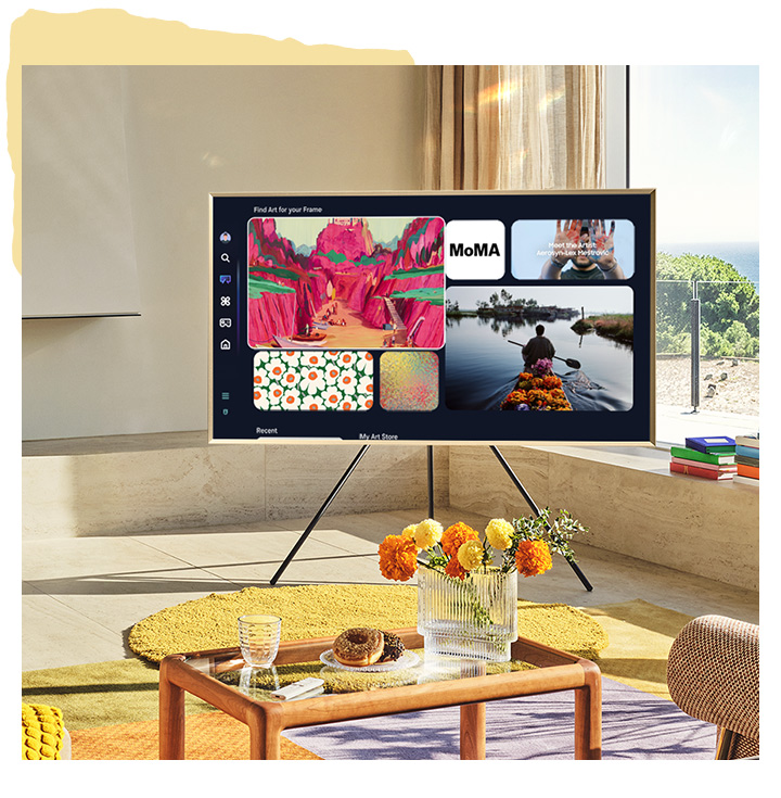 Телевизор Frame на подставке Studio Stand в гостиной показывает экран Art Home с некоторыми произведениями искусства, доступными в Art Home.