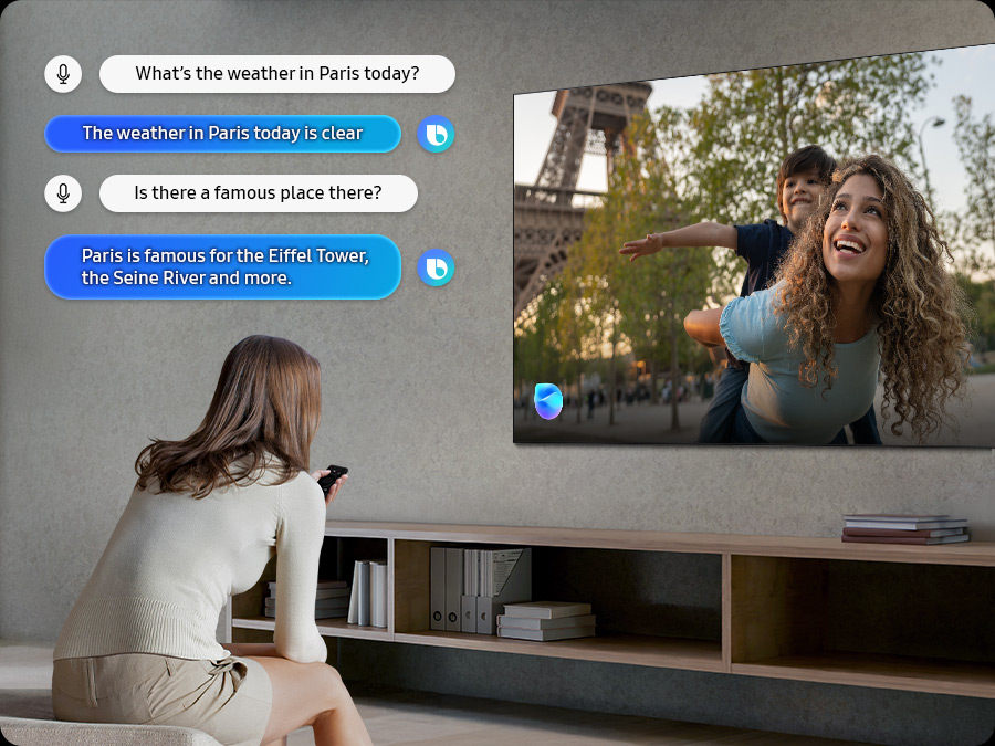 Женщина в гостиной разговаривает с Биксби через телевизор. Отображаются субтитры к диалогу. Какая погода сегодня в Париже? Погода в Париже сегодня ясная. Есть ли там какое-то известное место? Париж славится Эйфелевой башней, рекой Сена и другим.